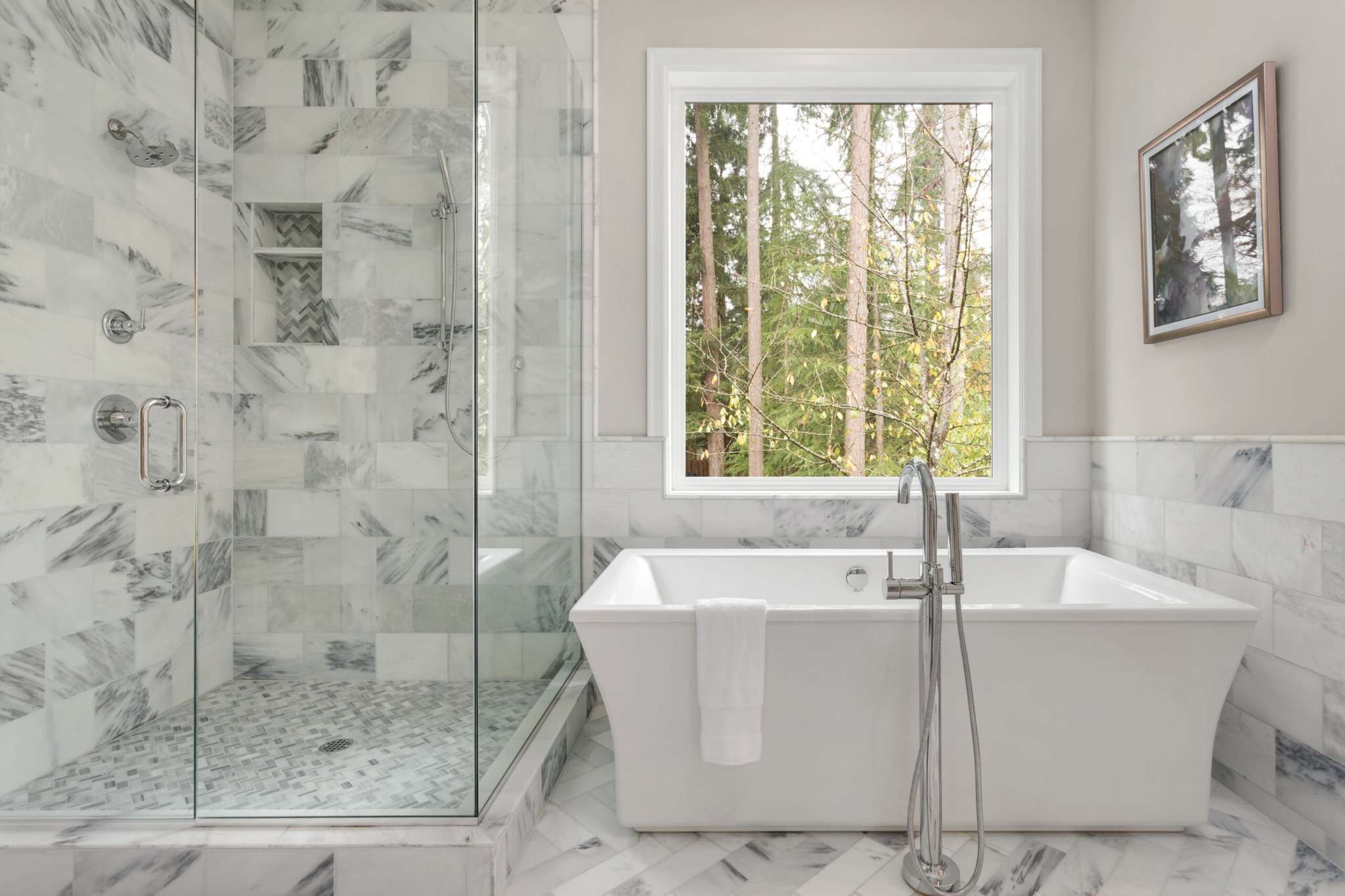 Luxury bathroom remodel with freestanding soaking tub, marble tile shower, glass enclosure, and natural light window in Greater Missoula.