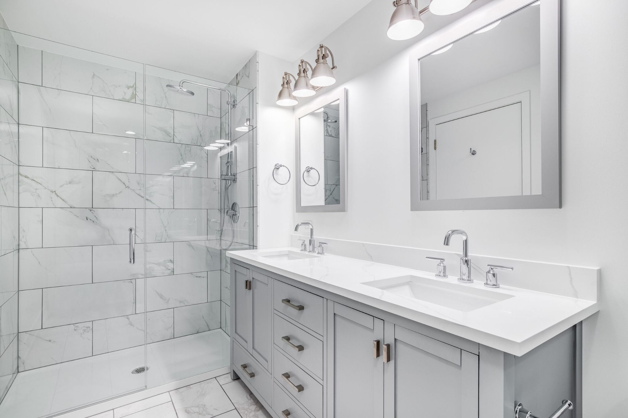 Bright bathroom remodel with double vanity, quartz countertop, glass walk-in shower, and marble tile walls in Greater Missoula.